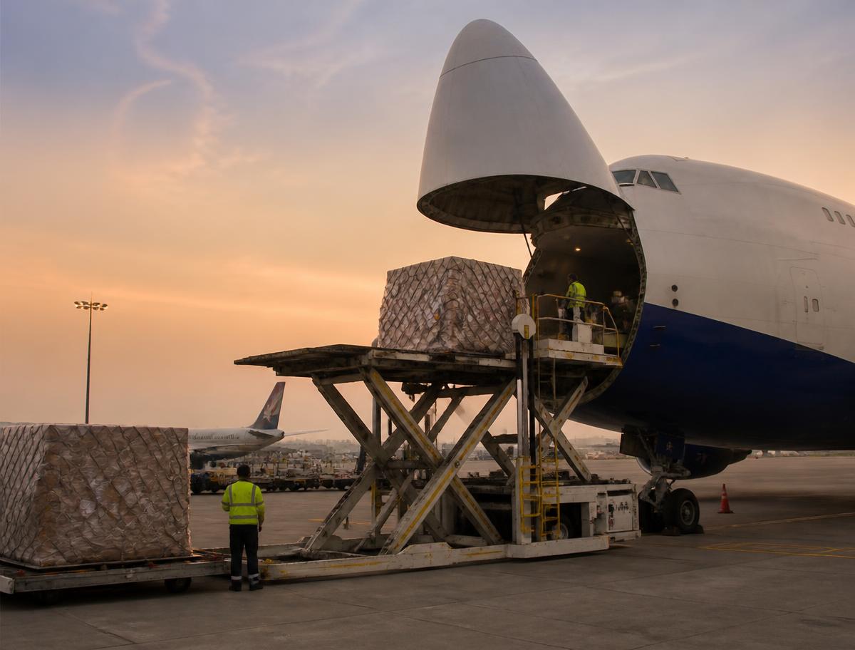 Cargo aircraft being loaded with freight pallets on the tarmac at dusk